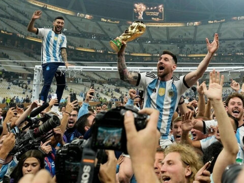 Lionel Messi giơ cao cúp vàng World Cup giữa đồng đội Argentina và đông đảo phóng viên